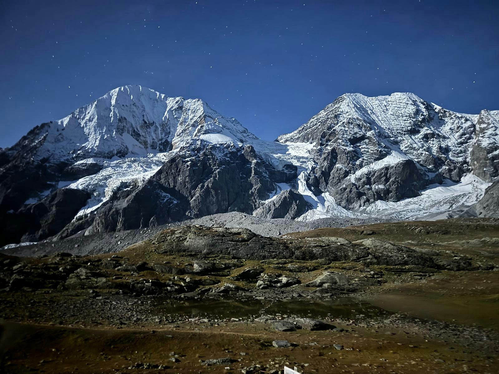 Snow-covered mountain summits beneath a starry blue sky
