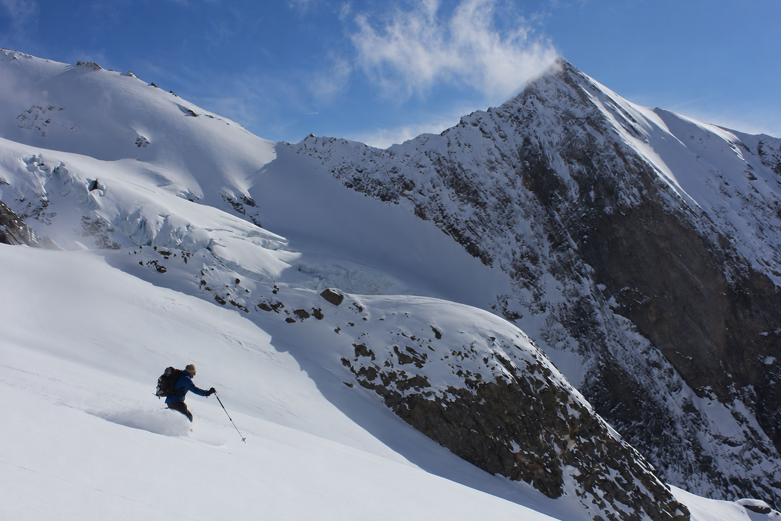 Single ski tourer descending beneath the steep face of Hochfirst